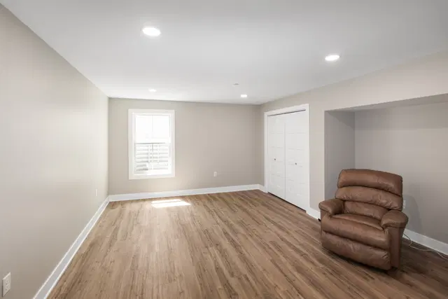 Brown recliner in a bright basement seating area with a window, white closet doors and wood-look flooring.