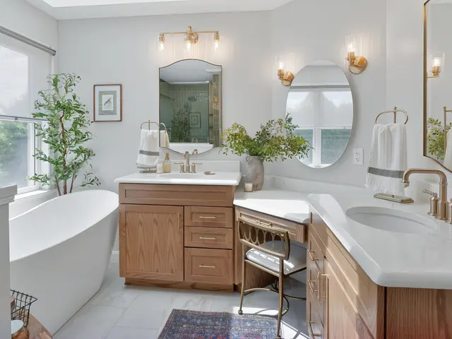Wood bathroom vanities with white countertops, arched mirrors and a seated makeup area beside the tub.