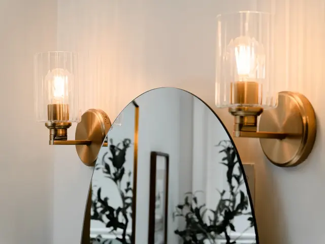 Gold-tone wall sconces with glass shades flanking an arched bathroom mirror.