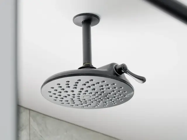 Black showerhead extending from a tiled wall above the glass shower.