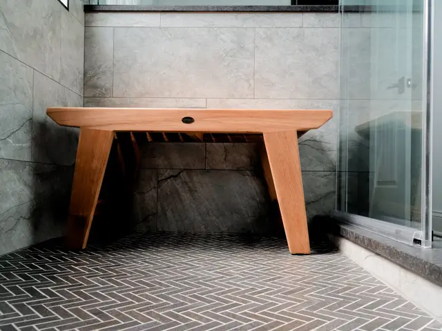 Wood bench and herringbone shower floor seen through the glass enclosure.