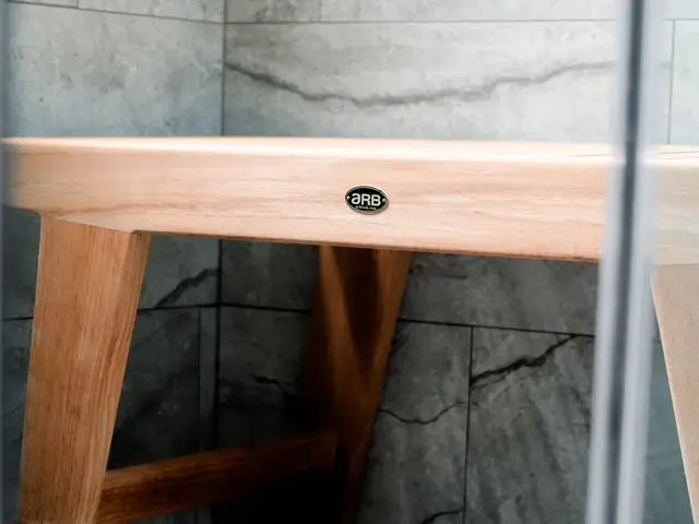 Close-up of the wood shower bench and its legs on gray tile.
