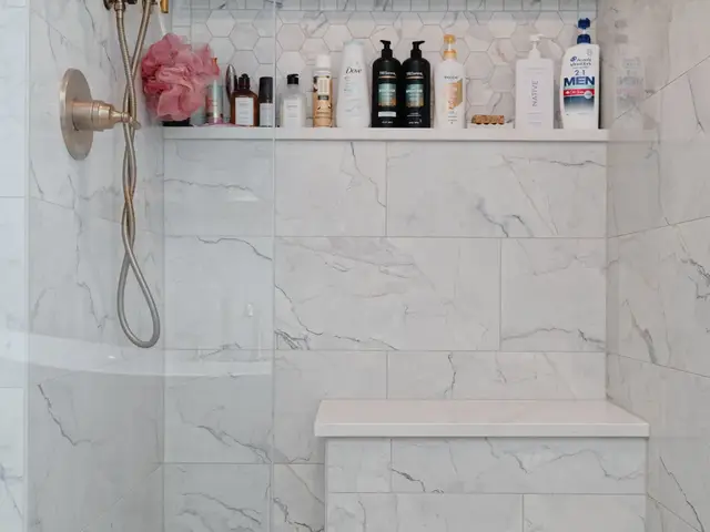 Vertical shower view with gold-tone fixtures, a long storage niche and a tiled bench.