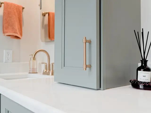 Vanity countertop beside the central blue-green cabinet, gold-tone hardware and orange towels.