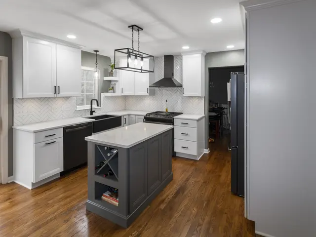 Finished kitchen with white cabinets, a gray island with a wine rack, black apron-front sink, herringbone backsplash and rectangular pendant light.