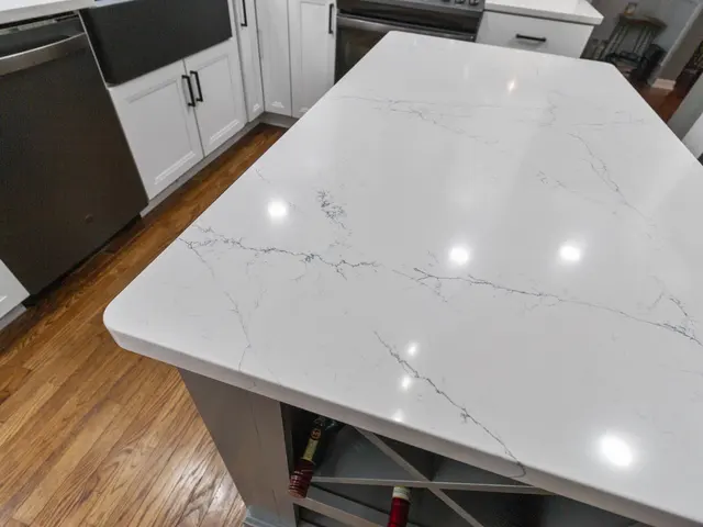 Close-up of the kitchen island's light countertop with gray veining above a gray built-in wine rack.
