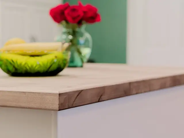 Close-up of the wood island countertop with a green bowl and red flowers.