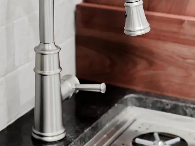 Close-up of the coffee-area faucet beside wooden cutting boards and a stainless sink.