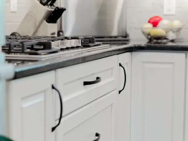 White drawers and base cabinets beneath the gas cooktop and dark kitchen countertop.