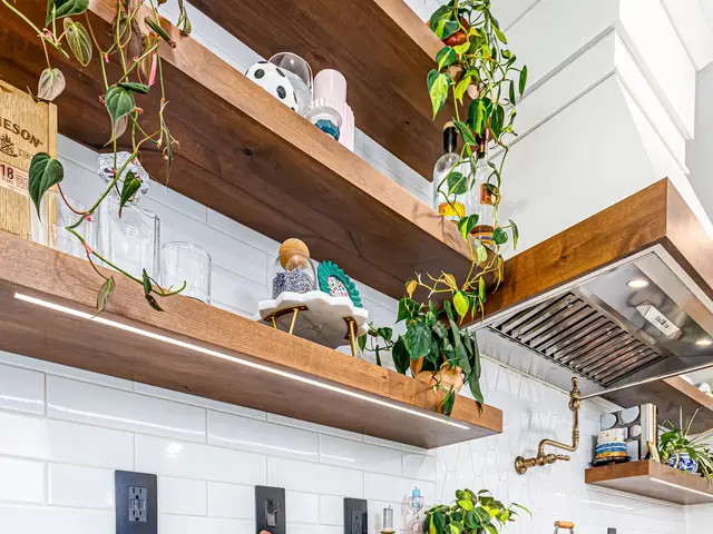 Floating wood shelves with mugs and trailing plants beside the wood-trimmed range hood.