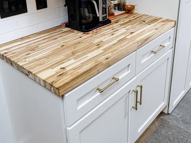 White coffee-area cabinetry with gold-tone pulls beneath a striped wood countertop.